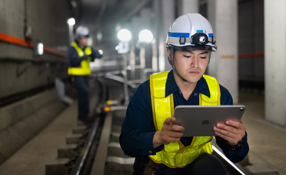 穿著安全背心與安全帽的工作人員，在 Tokyo Metro 隧道內執行維護作業並查看 iPad。
